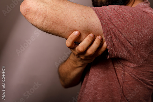 Slika na platnu Close-up of a man holding his elbow due to sudden sharp pain and discomfort