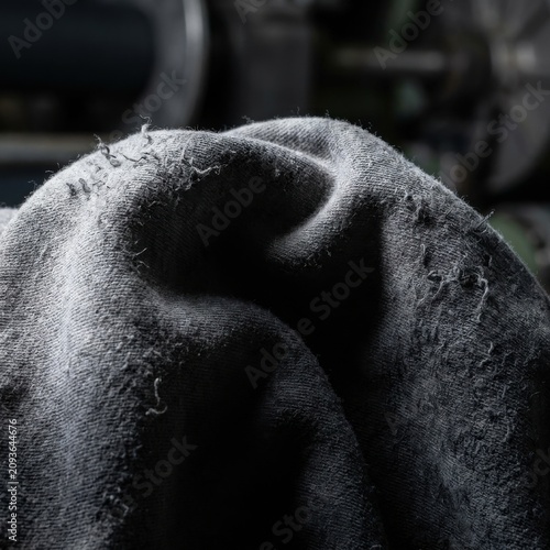 Close-up of Damaged Gray Knit Fabric with Pilling and Frayed Threads in Moody Industrial Setting for Textile Waste and Quality Control Messaging