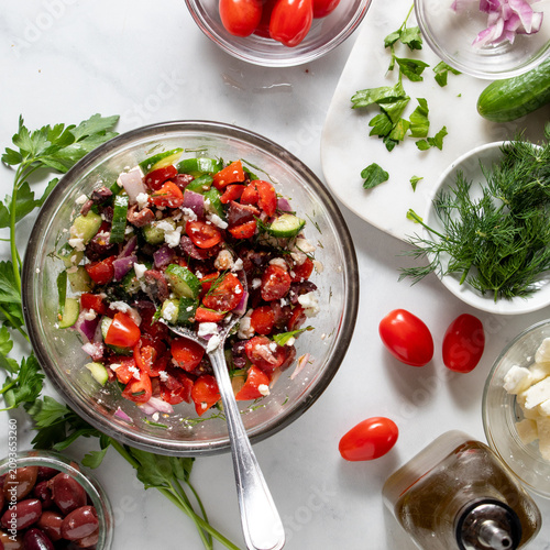 A freshly made mediterranean salad with ingredients all around.