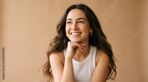 Young woman with long curly hair smiling and resting chin on her hand well being portrait lifestyle positive