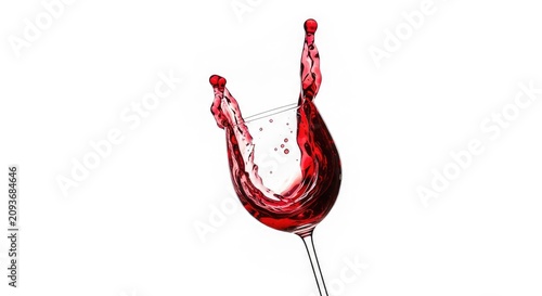 Vibrant red wine erupts in a dramatic splash from a clear glass, with shimmering liquid droplets frozen in mid-air against a clean backdrop, glass, flow, still life