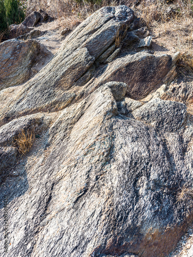 Foto Angled layers of gray schist rock formation illuminated by bright sunlight