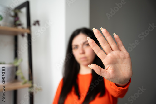 Fotografía Woman in bright attire making a stop gesture with her hand indoors