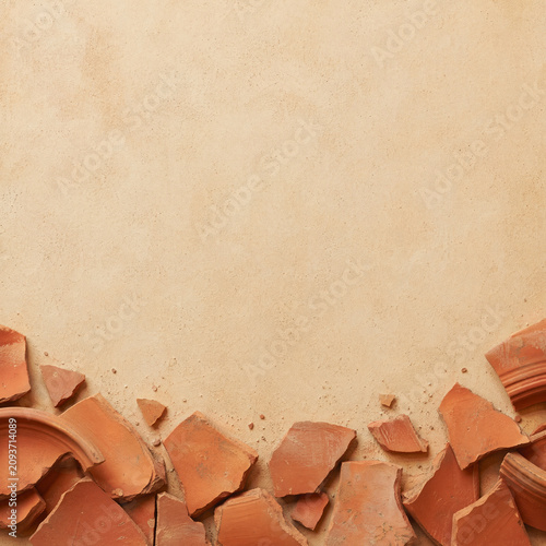Scattered broken terracotta pottery shards on rustic textured surface