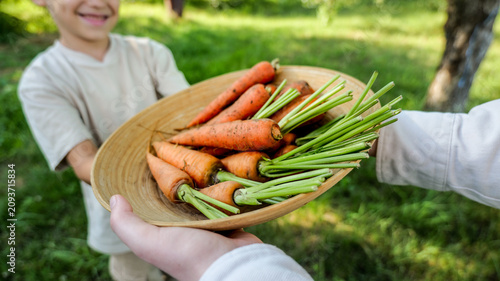 Quadro su tela Child proudly presents a bowl of freshly harvested carrots from the garden