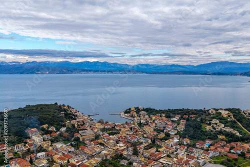 Panoramic Aerial Shot of Kassiopi Bay and Coastal Village Against Blue Sea and Mountains Corfu Greece