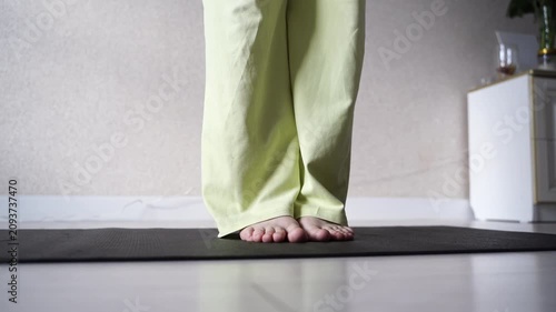 Static Shot Of Barefoot Woman Standing On Yoga Mat With Subtle Balance Shift In Bright Home Room, Showing Indoor Wellness Practice And Calm Posture.