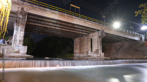 Tableau sur toile A bridge with water flowing beneath it, at night.
