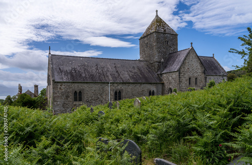 Bild auf Leinwand The historic medieval stone buildings of Penmon Priory situated on the eastern tip of Anglesey in North Wales under a blue sky