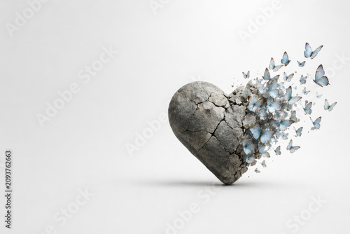 Cracked stone heart turning into blue butterflies. Space for text.