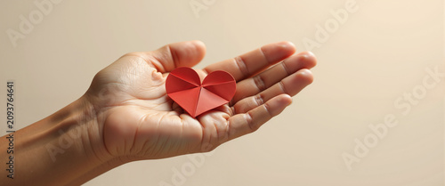 Open palm holding origami heart for emotional support and self care mental health campaigns