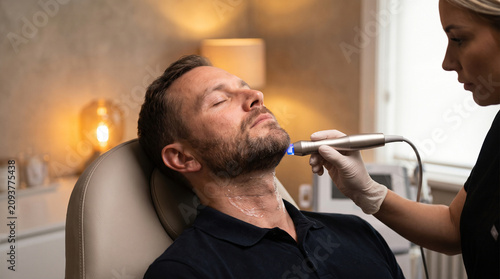 Man receiving jawline laser skin tightening treatment clinic