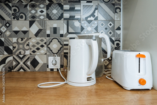 Fotografie White electric kettle and toaster on wooden kitchen countertop with patterned ti