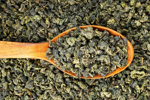 Green oolong tea scoop on flat background wooden spoon macro