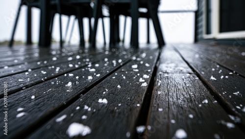 Close up of hail on a wet wooden deck with chairs out of focus