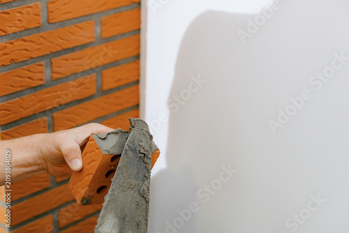 A young man makes brickwork on the chimney of a fireplace.