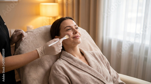 Relaxed woman receiving facial gel mask treatment spa
