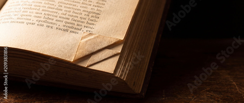 Folded pages of old vintage book with dog-eared corners on textured yellowed paper resting on a dark wooden table, perfect for library, historical research, and literature concepts