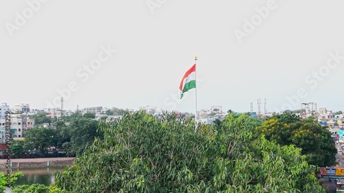 Video of the Indian national flag waving on a tall flagpole above a city
