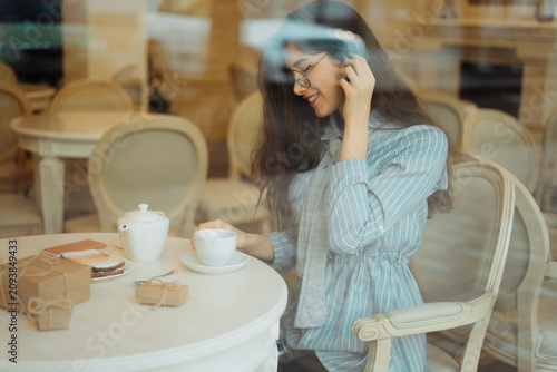Tableau sur toile beautiful asian girl drinking tea in cafe while waiting for someone and having p