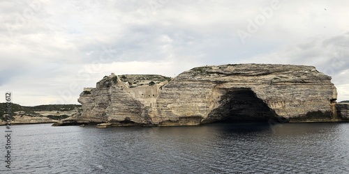 Fotografie Limestone Cliffs and Sea Cave Approaching Bonifacio by Water on the Coast of Cor