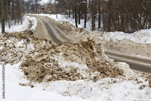 Obraz na plátně Grimy snowdrifts line a freshly plowed winter road
