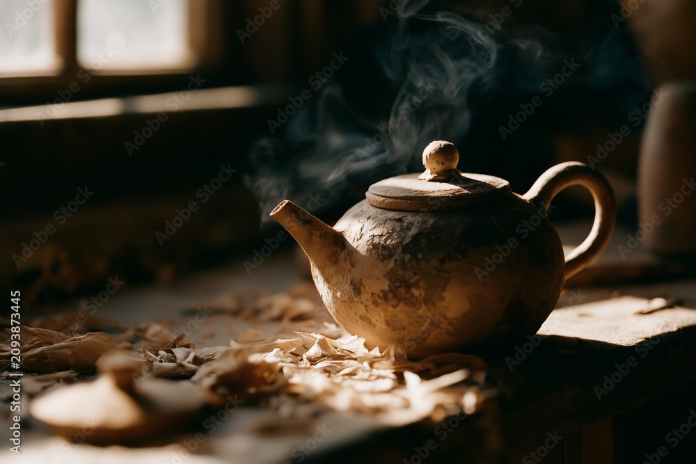 Fototapeta premium Weathered clay teapot pouring steam on sunlit workshop bench