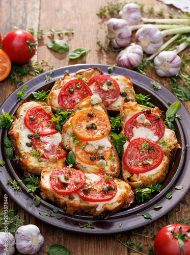 Grilled sourdough bread sandwiches, bruschettas with  cheese, tomatoes, capers and garlic seasoned with aromatic herbs on a ceramic plate, close-up view