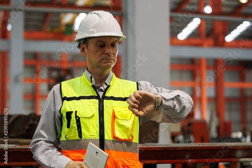 Foto Engineer checking time on watch at industrial factory floor