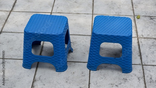 a pair of square lightweight plastic chairs sitting on a grey paved terrace floor during the day.