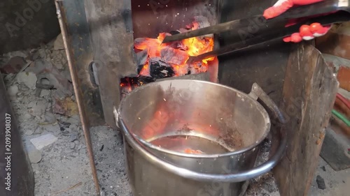 Close-up of a juicy beef steak being grilled over an open fire on a traditional charcoal stove. The footage captures the intense heat of glowing red embers, rising smoke, and the authentic outdoor coo