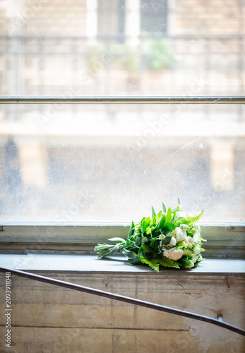 Fotografía green white bouquet lying on the large  window  sill