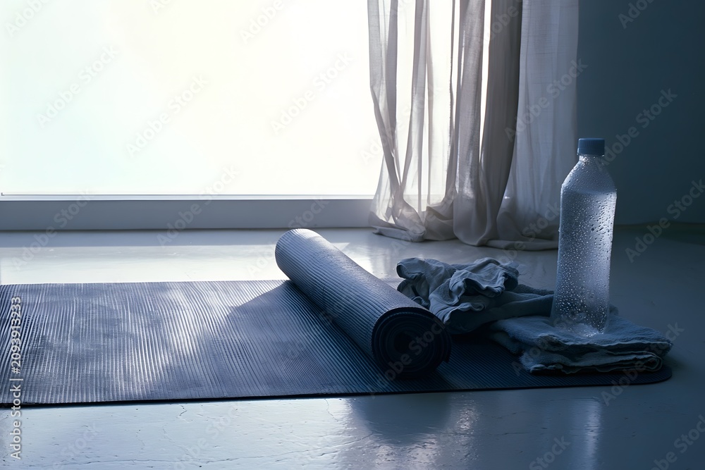 Fototapeta premium Home yoga space with rolled mat on pale concrete floor