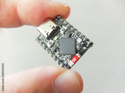 Hand holding a small black microchip microcontroller development board with type-c