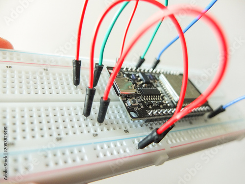 фотографія Microcontroller board with connected colorful jumper wires on electronic breadboard