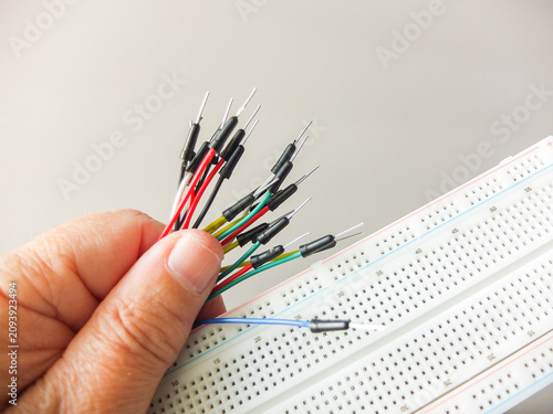 Foto Hand holding a bunch of colorful jumper wires next to an electronic breadboard