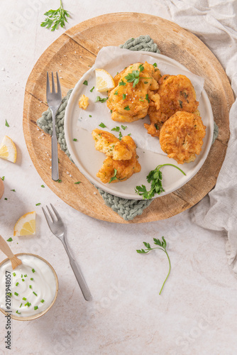 Obraz na plátně Crispy golden cod fritters on a rustic plate with fresh parsley, lemon, and a cr