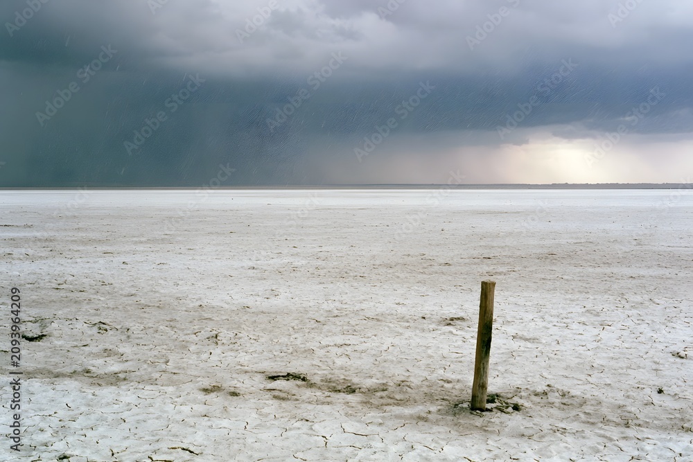 Fototapeta premium Lone Wooden Stake on Salt Flat During Sudden Hailstorm