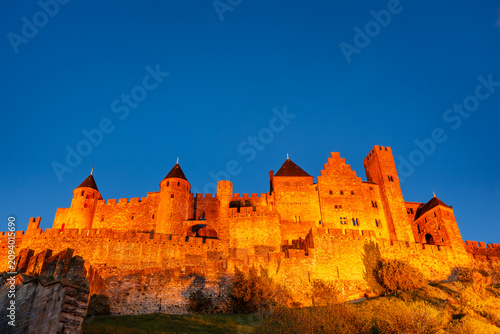 Foto Medieval fortress in France Carcassonne France illuminated at twilight on cloudless evening