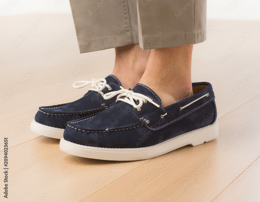 Naklejka premium Close-up Action View of Feet in Dark Blue Loafers on Light Wooden Floor with Khaki Pants in Clean Environment