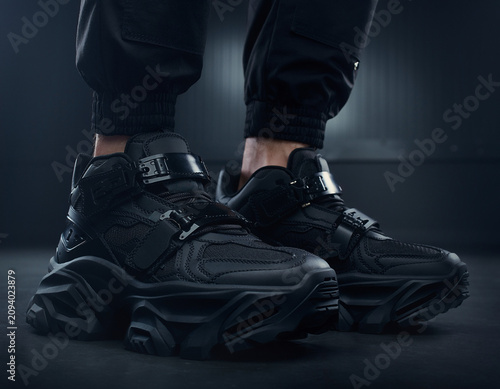 Close-up View of Athletic Shoes on a Person's Feet in a Dark Urban Environment with Moody Lighting and Dramatic Shadows from the Right Side with Focus on Shoe Design and Features