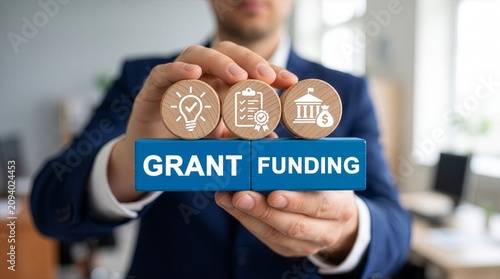 Man holding colorful blocks with icons and inscription GRANT FUNDING. Concept of grants and funding.New