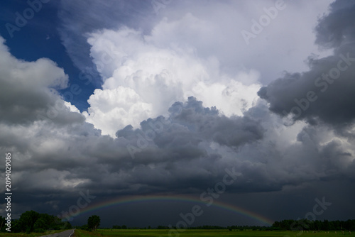 Rainbow in the sky with dark storm clouds and sun rays