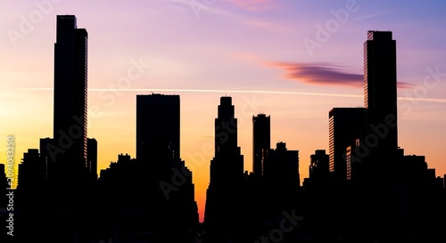 City skyline silhouettes against a pastel sunset sky