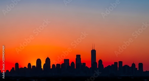 Cityscape silhouette against vibrant orange and blue sunset sky.