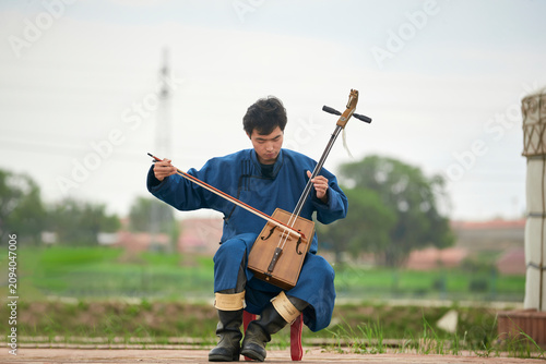 Canvastavla A musician dressed in Mongolian attire playing the morin khuur (horsehead fiddle
