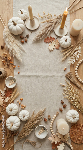 neutral Halloween flat lay background featuring white pumpkins, beige leaves and autumn decorations arranged around a clean central copy space.