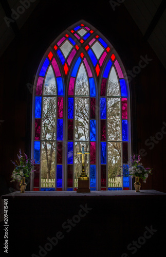 Fotografie Vibrant stained glass window with cross and flowers inside a church