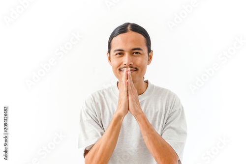 Fotografía Young Asian man with long hair showing a polite respectful greeting gesture