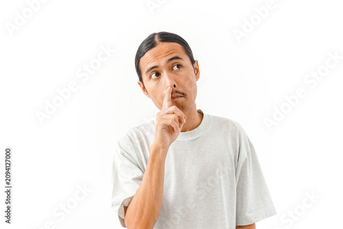 Asian man making a hush gesture with his finger on a white background